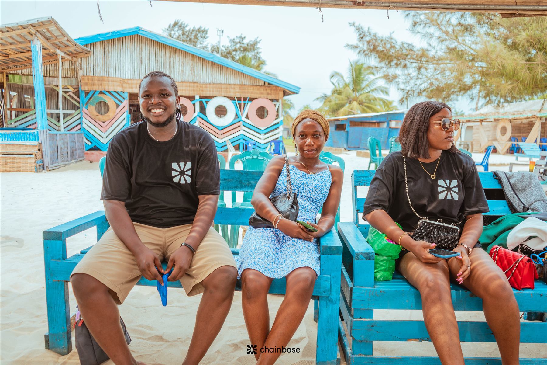 Three attendees in Chainbase branded t-shirts smiling at Beachfest