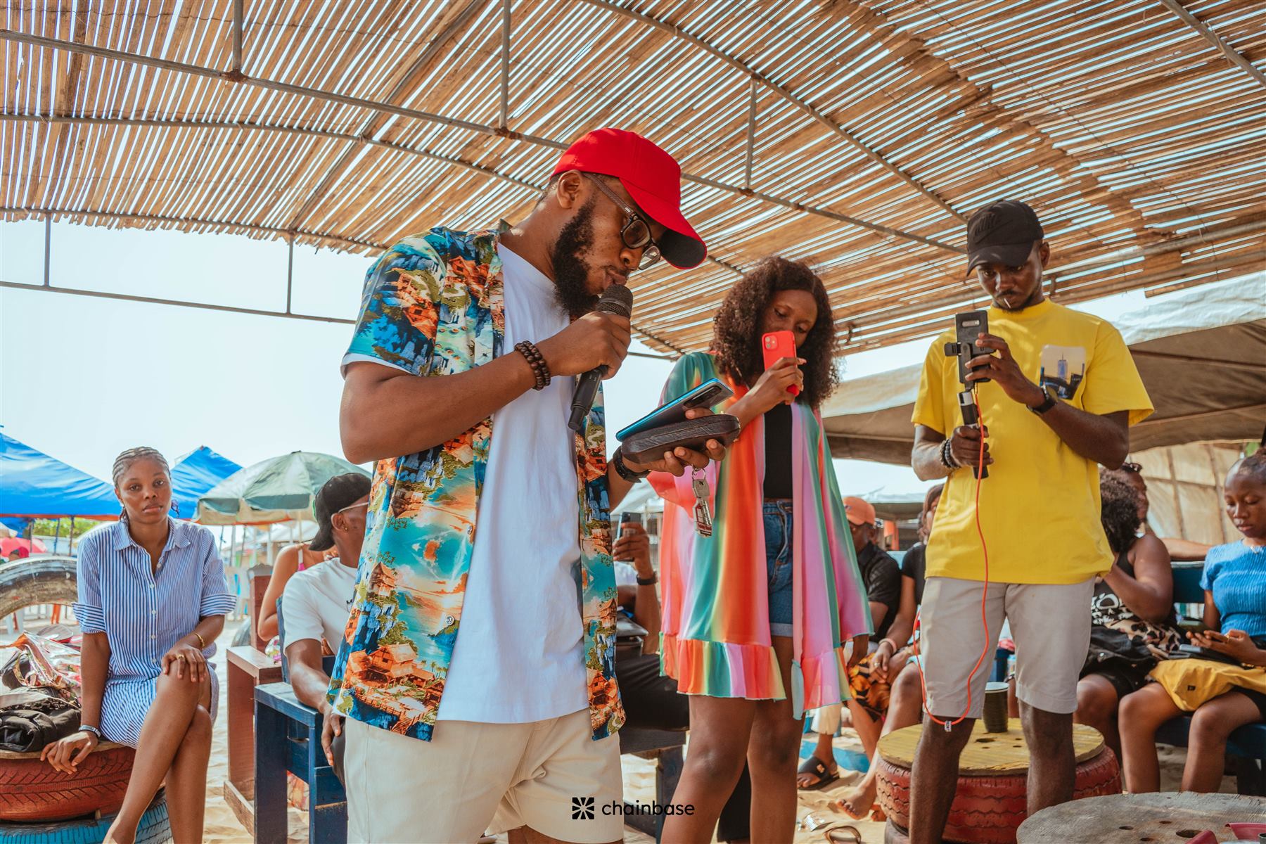 A host speaking into the microphone at Chainbase Beachfest as attendees film on their phones