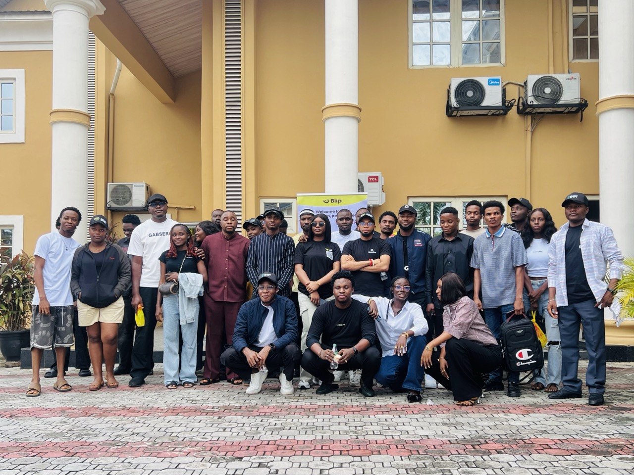 The full Money Moves Uyo team and attendees posed outside the venue, Blip banner visible